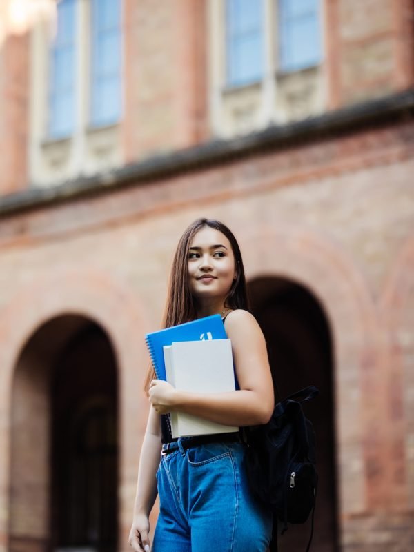 portrait of young student holding book at campus